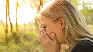 woman sneezing outside