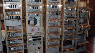 A photo of a stack of computer towers with many wires and electronic parts