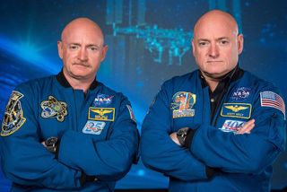 Scott and Mark Kelly stand next to each other in NASA uniforms.